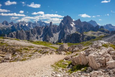 İtalyan Dolomitleri 'nde güneşli bir yaz günü. Kayalık tepeler bazı yerlerde karla kaplıdır. Önplanda boş bir yürüyüş yolu var