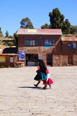 Taquile Adası, Titicaca Gölü, Peru - 25 Haziran 2019 - Geleneksel elbise ve Katoliklikte gösterildiği gibi, sömürge cihetinden etkilenen Taquile Adası'ndaki ana köyden manzara.