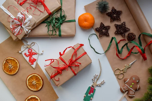 Cadeaux en papier artisanal, attachés avec un ruban rouge et vert, entourés de bagatelles de Noël — Photo