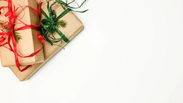 Deux coffrets cadeaux de Noël emballés dans des rubans kraft et rouge et vert sur fond blanc — Photo