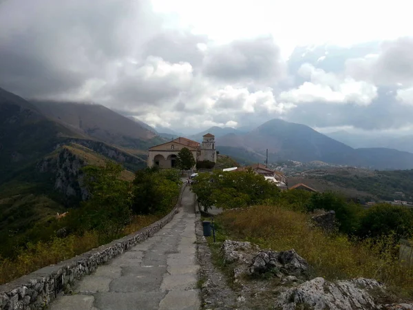 Güzel bir kilise ve dağlar ve bulutlar, Maratea, Basilicata, Potenza, İtalya ile kasvetli bulutlu gökyüzü manzarası.