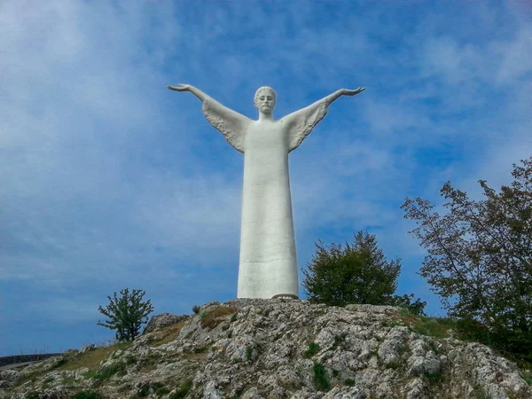 A huge snow-white statue of Christ on the top of a mountain against a blue sky and clouds in Maratea, Basilicata, Potenza, Italy