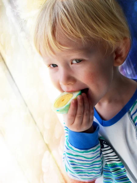 Blonde baby bites Easter egg for breakfast