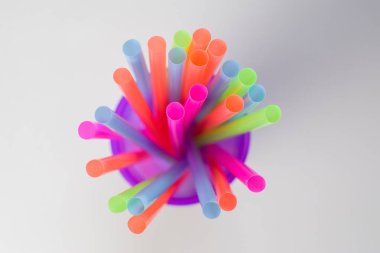 Mor bir cam, beyaz bir arka plan üzerinde üstten görünüm çok renkli parlak plastik tübüllerin