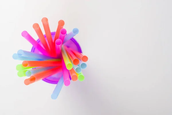 Beyaz bir arka plan, metin eklemek için boş bir yer üstünde mor bir cam parlak çok renkli plastik tübüllerin