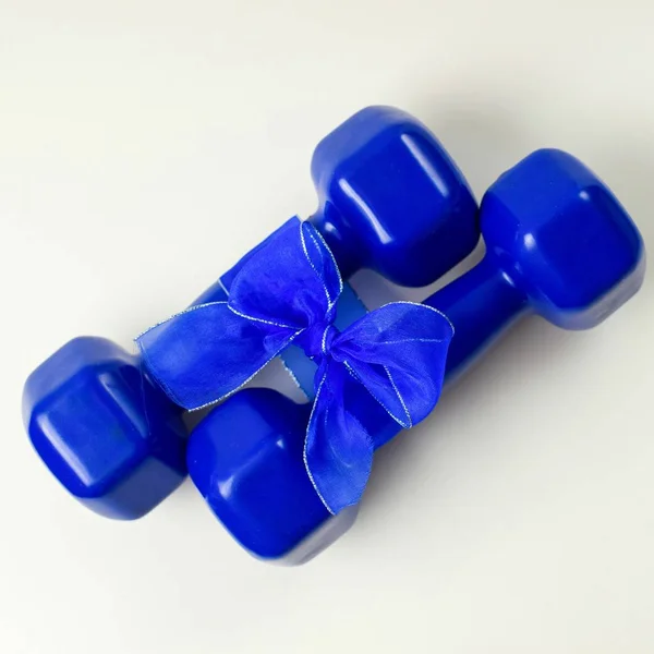 İki mavi dumbbells hediye ile beyaz arka plan, spor ve sağlıklı konsept yay