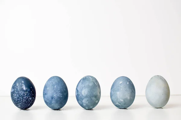 Πέντε χρωματιστές μπλε, γκρι, πέτρα, όπως μάρμαρο αυγά στέκονται κάθετα από το σκοτάδι στο φως — Φωτογραφία Αρχείου