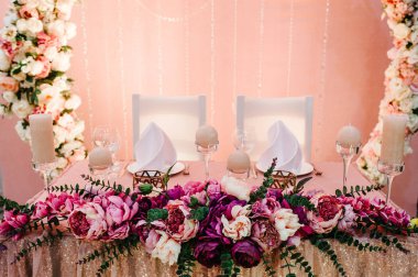 Kompozisyon menekşe, mor, pembe çiçek ve yeşillik ayakta düğün alanında hizmet masada. Tablo yeni evliler yemekleri ve çatal bıçak takımı ile görev yaptı. Yakın çekim.