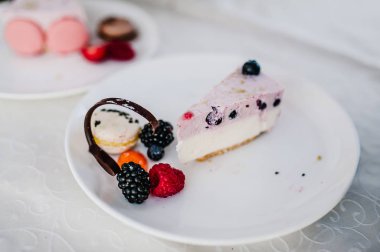 Bir parça pembe kek dekore edilmiş taze çilek ile Doğum: çilek, ahududu, kuş üzümü, böğürtlen, yaban mersini ve macarons tatil için.