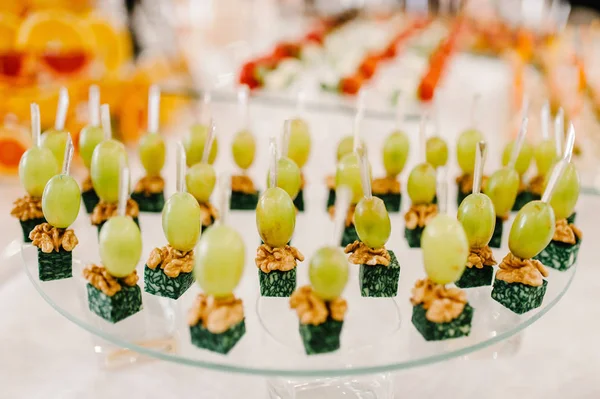 Snack from grapes, cheese and nuts. Light snacks in a plate on a buffet table. Assorted mini canapes on table.Decorated delicious table for a party goodies for the wedding on banquet area. Close up.