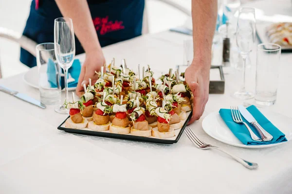 Garson gurme meze, mini sandviç, crostini farklı Topingler ile çeşitli ile masaya bir tabak koyar. Önden görünümü yukarıdaki. Çeşitli İtalyan meze bruschetta.