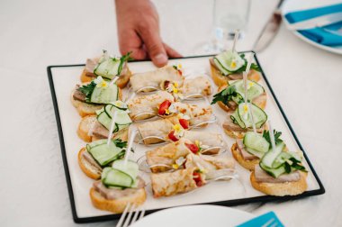 Garson gurme meze, mini sandviç, crostini farklı Topingler ile çeşitli ile masaya bir tabak koyar. Önden görünümü yukarıdaki. Çeşitli İtalyan meze bruschetta.
