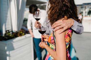 Şerefe! İnsanlar kutlamak ve bardak şarap tost için yükseltmek. Grup erkek ve kadın şehir manzaralı çatı katındaki restoranda köpüklü şampanya ile tezahürat.