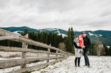 Küçük kızı soğuk kış dağlarda poz ile genç neşeli aile portresi