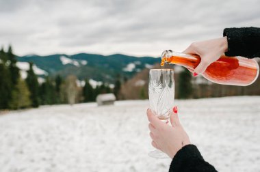 Kadının görünümü Kapat kış Dağları arka plan üzerinde cam içine dökme şampanya eller