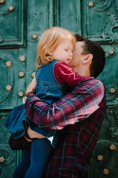 Young dad hugging little blonde daughter on vintage old door background