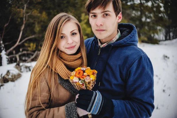 年轻夫妇手牵着花束干花在冬季景观 — 图库照片