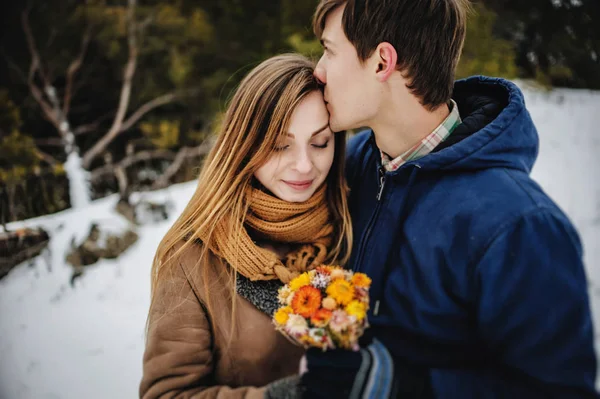 手の花束を抱いた若い夫婦乾燥した冬の風景に花 — ストック写真