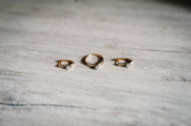 Ahşap arka plan üzerinde şık gümüş küpe, altın yüzük