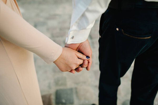 Close view of romantic couple holds hands together outdoor
