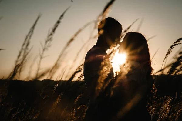 Silhouette of young couple hugging and kissing in autumn field