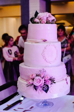 Pembe çiçek ve yeşillik şenlikli masada beyaz düğün pastası 