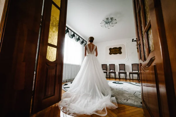 bride standing in luxury wedding dress near window.