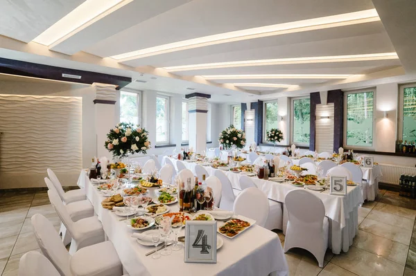 Festive table decorated with composition of flowers and greenery, candles in wedding banquet hall