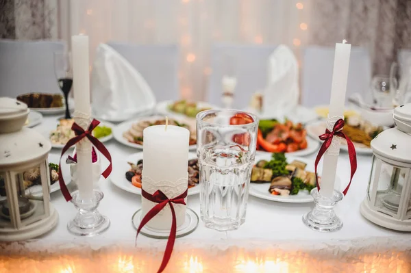 Close view of white wedding candles with red bows on table