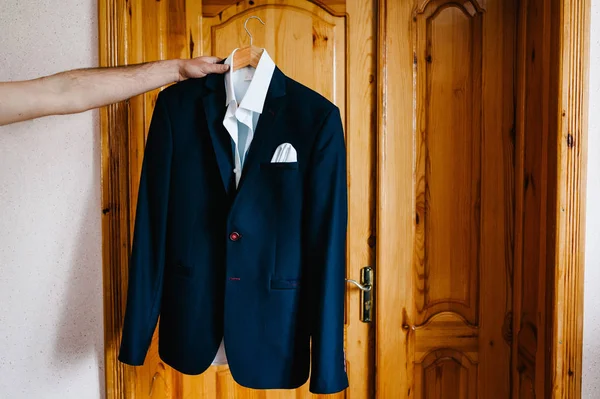 Holding kahverengi ahşap kapı arka plan üzerinde beyaz gömlek ve mavi ceket damat 