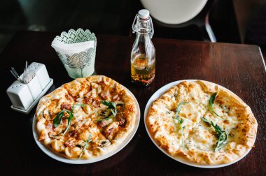 Roka ve et kahverengi ahşap masa üzerinde iki İtalyan pizza dört peynir