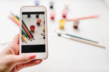 kadın alarak resmi renkli kalemler, suluboya, boyalar, fırçalar, sketchbook, beyaz kağıt üzerinde beyaz tablo ile çalışma alanının smartphone için