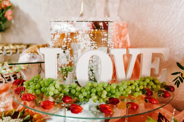 Plate with fresh fruits with word love for wedding party