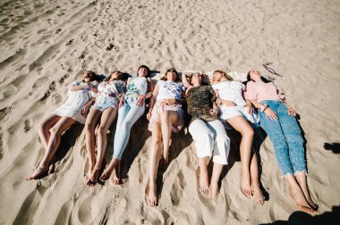 Ayakları üzerinde kum plaj yatarken gösteren güzel mutlu ince şık seksi genç kız. Stil boho parti. Hen-partiler akşam kızlık. 