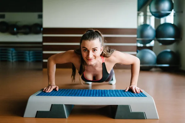 スポーティな女性 Gym コンセプトでエアロビクス ステップ プラットフォームで腕立て伏せをやって — ストック写真