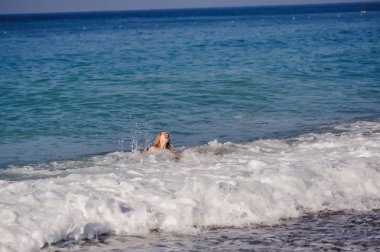 Genç kadın yüzme ve dalgalı denizde eğlenmek