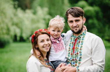 Genç aile ile oğul içinde nakış gömlek yürüyüş ve sahip olan eğlence içinde yeşil yaz Park 