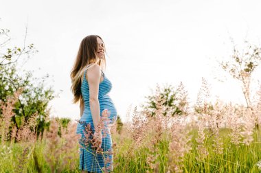 Yeşil alanda yaz güneşi zevk hamile genç kadın  