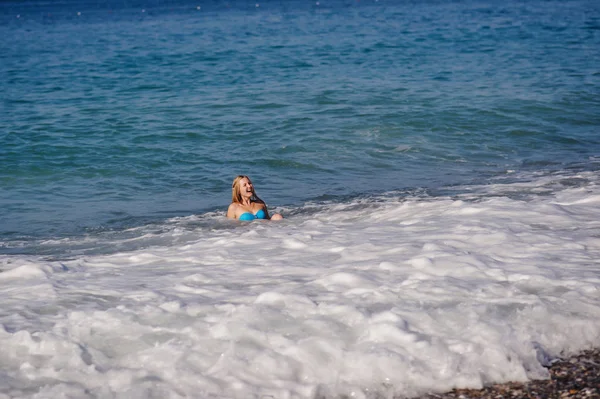 Genç kadın yüzme ve dalgalı denizde eğlenmek