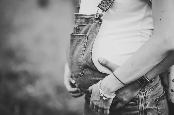 緑の公園で妊娠中の妻の胃を抱きしめた男 — ストック写真