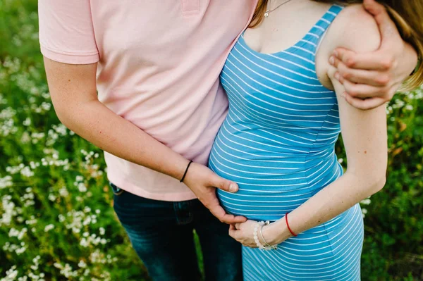 緑の公園で妊娠中の妻の胃を抱きしめた男 — ストック写真