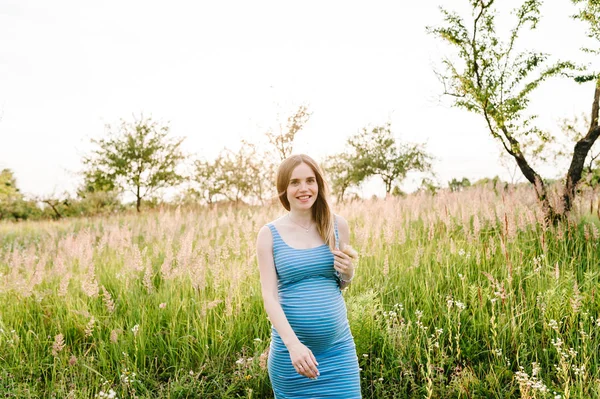 年轻的怀孕快乐的女人走在绿色的避暑公园 — 图库照片