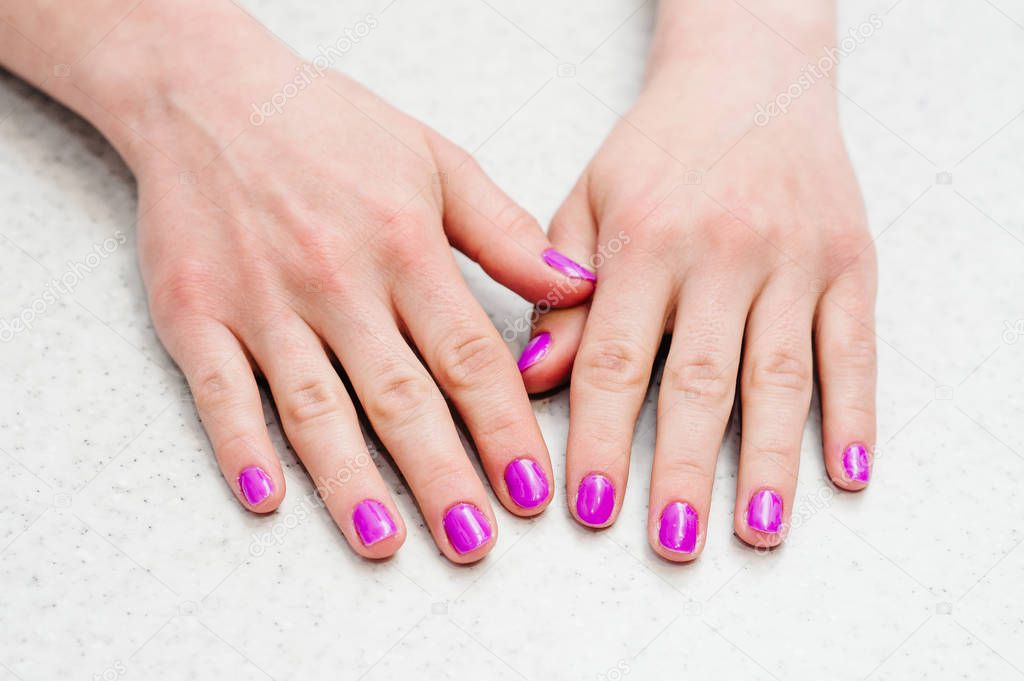 Close view of female hands with bright pink manicure 