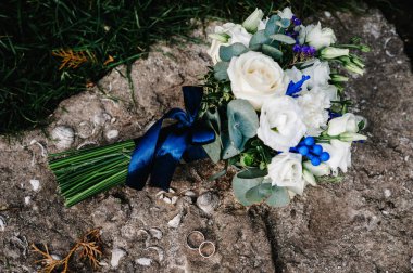 Taş arka planda Bush güller, eustomas ve altın alyans ile şık düğün buketi