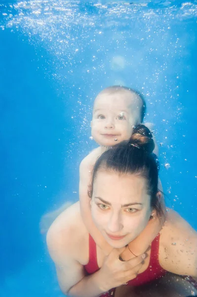 若いですお母さんはプールで水中で泳ぐ息子を教える — ストック写真