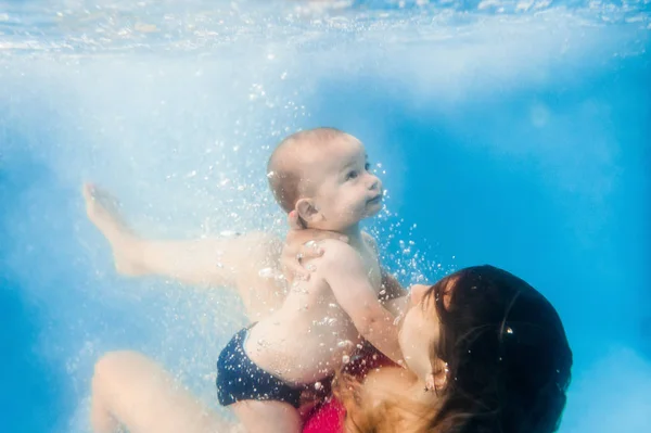 若いですお母さんはプールで水中で泳ぐ息子を教える — ストック写真