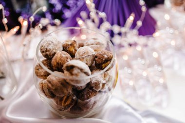 Ceviz, cam bir tabakta yoğunlaştırılmış süt, vazo. Işık arka plan masasında. Kek, turta, tabakta cam bir yüzey içinde fındık. Tatlı. Tatlılığı. Nazik bir ton. Kapat.