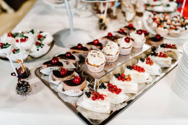 Güzel masa. Böğürtlenli kremalı kek ve kek. Şekerli masa, şeker, açık büfe. Düğün için parti malzemeleri için tatlı masası. Kapat..