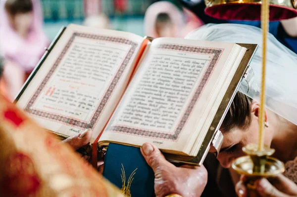 The priest holds and read the Bible in his hands. Priest during a wedding ceremony, celebrate a mass at the church. Close up.