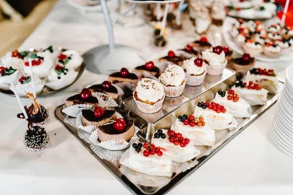 Güzel masa. Böğürtlenli kremalı kek ve kek. Şekerli masa, şeker, açık büfe. Düğün için parti malzemeleri için tatlı masası. Kapat..